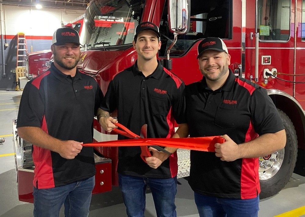 Redline Fire Watch New Jersey ribbon-cutting ceremony with franchise owners and founder standing in front of a fire truck at a local fire station.